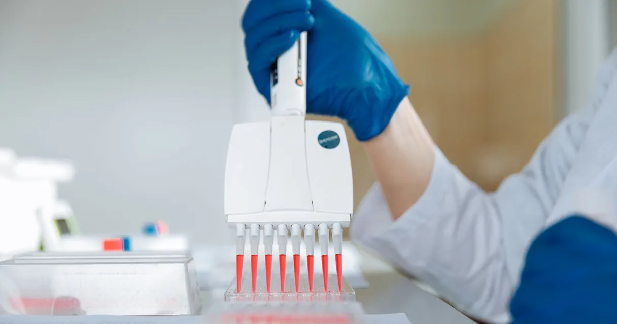 Pesquisadora usando micropipeta multicanal em laboratório